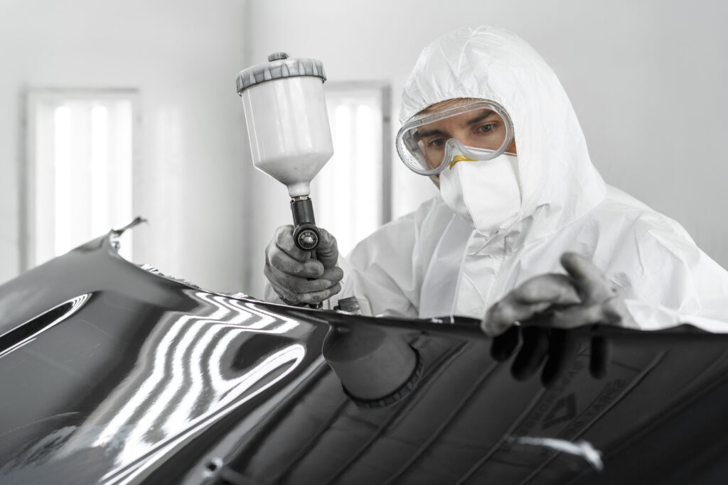 male-painter-using-gun-paint-car-shop